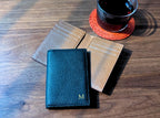 Three leather coasters on a wooden surface with a cup of tea.