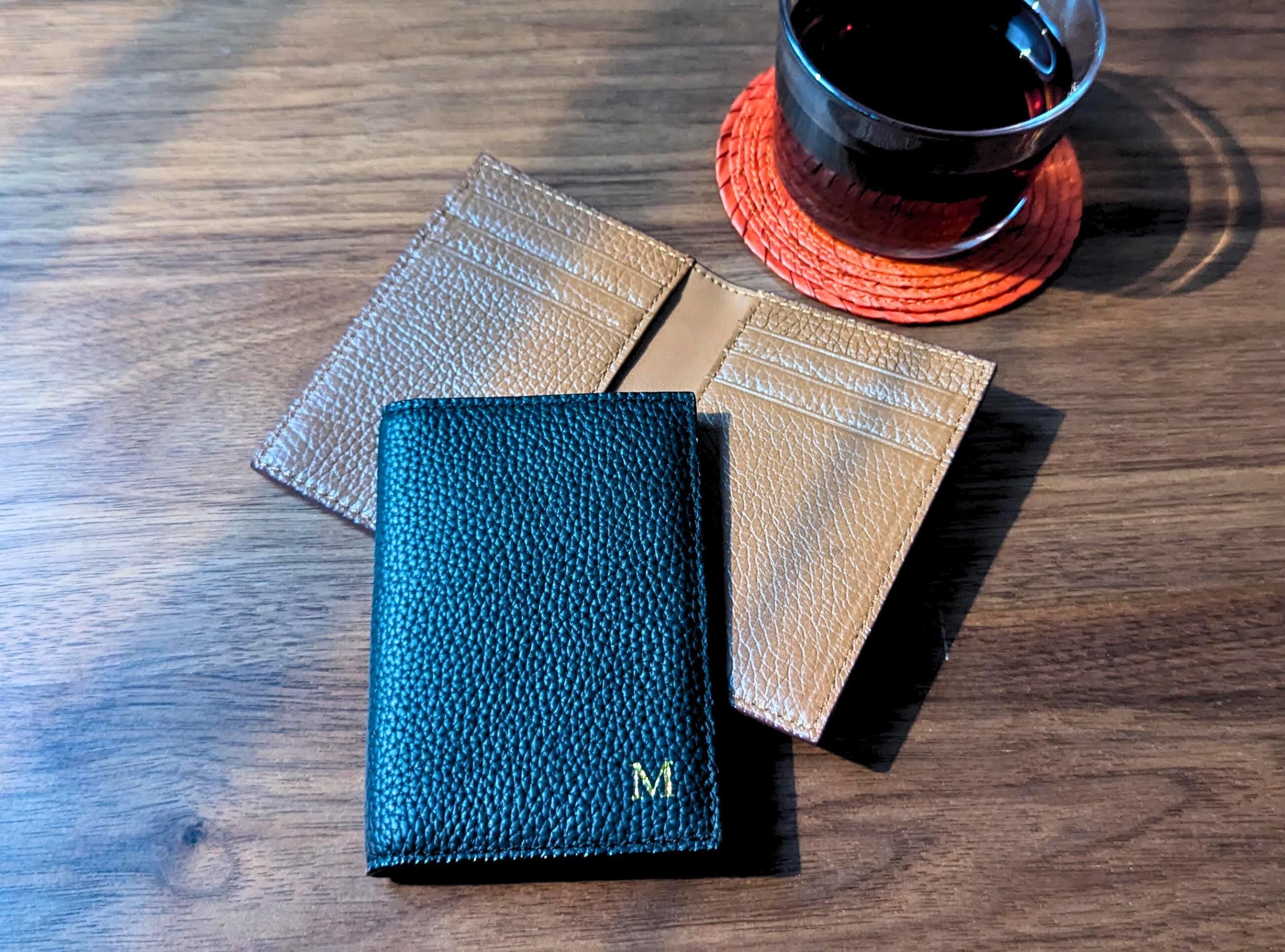 Three leather coasters on a wooden surface with a cup of tea.