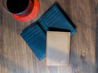 Three leather wallets on a wooden surface with a cup of coffee.