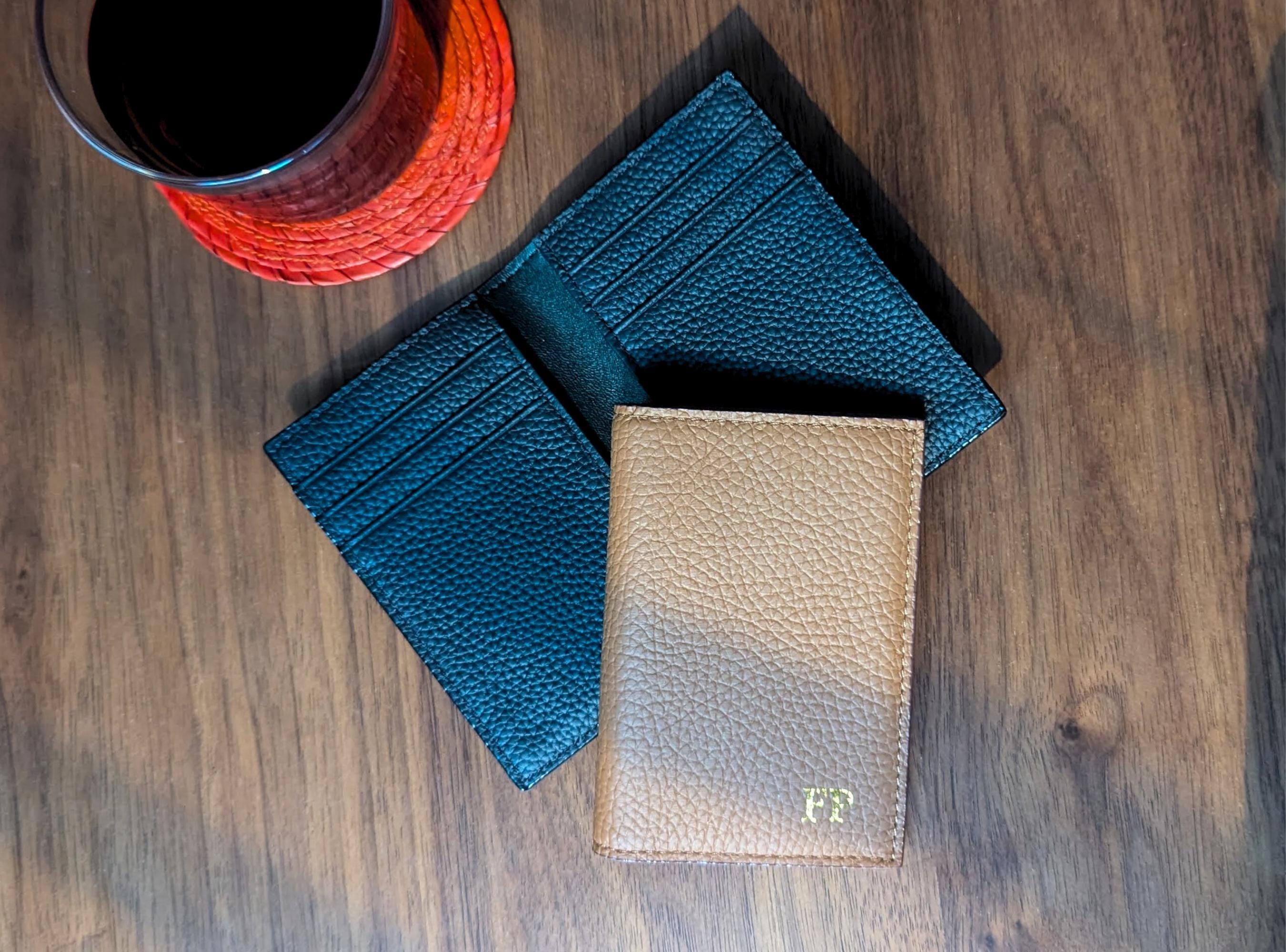 Three leather wallets on a wooden surface with a cup of coffee.