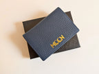 Blue textured wallet with custom branding on a beige background with gold emboss.