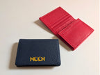 Navy wallet with custom branding and a red wallet open on a light beige background