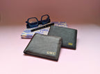 Two genuine leather wallets with custom initials on a pink surface