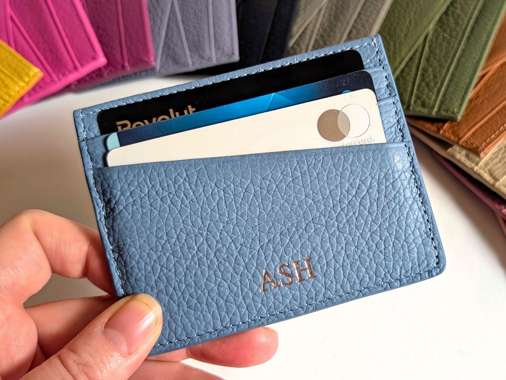 Collection of colorful leather card holders with initials on a white background