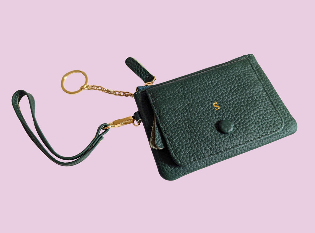 Green wallet with wrist strap on a pink background