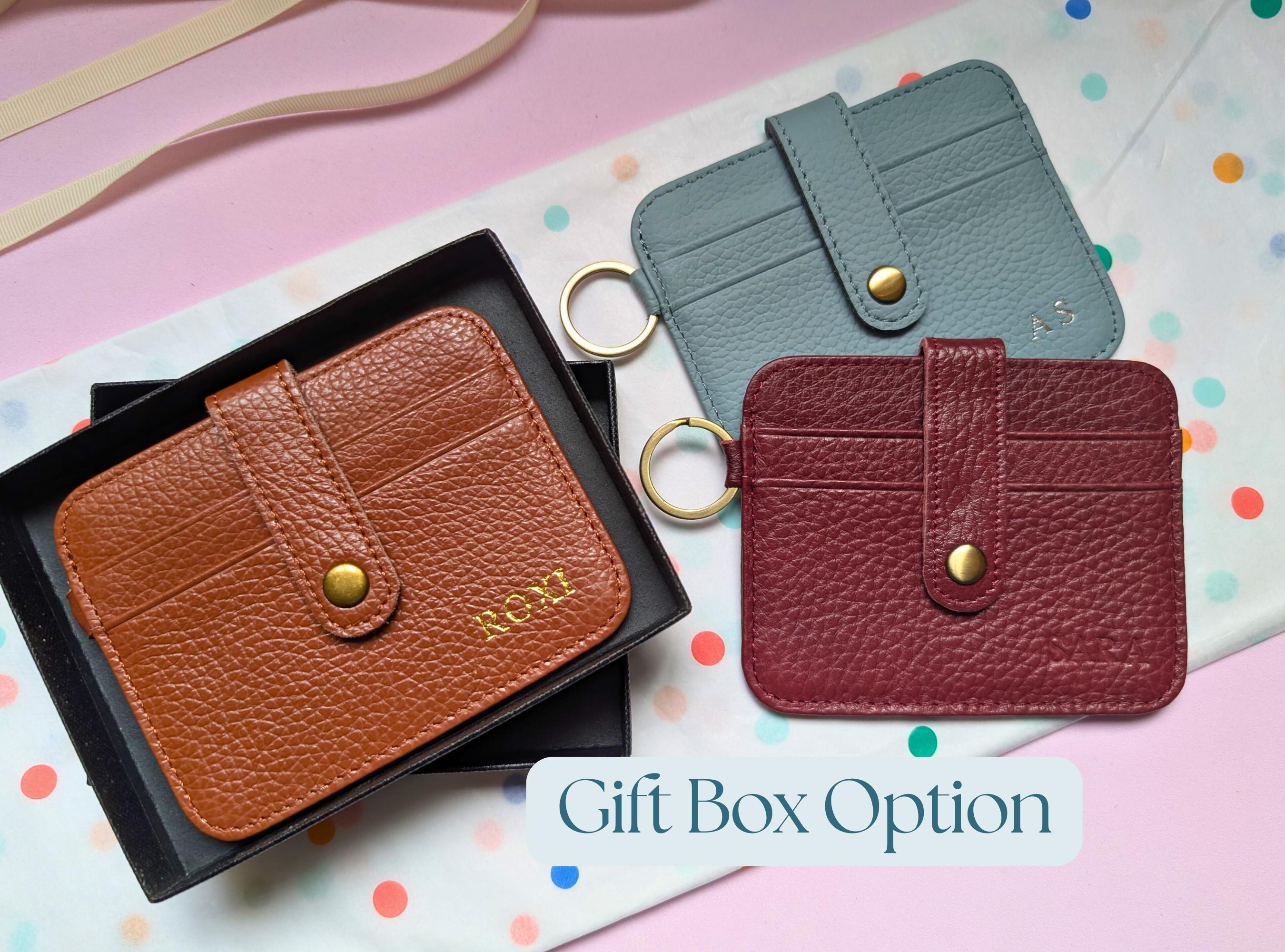 Three leather card holders in brown, gray, and red on a colorful polka dot background with 'Gift Box Option' text. Featuring personalisation.