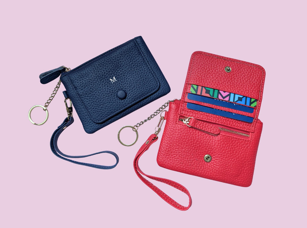 Blue and red wallets with wristlets on a pink background