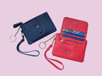 Blue and red wallets with wristlets on a pink background