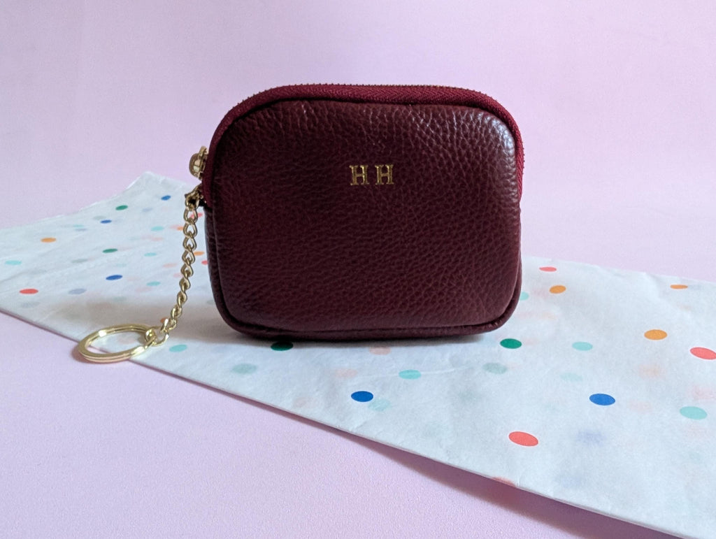 Maroon leather pouch with gold chain on a polka dot fabric background