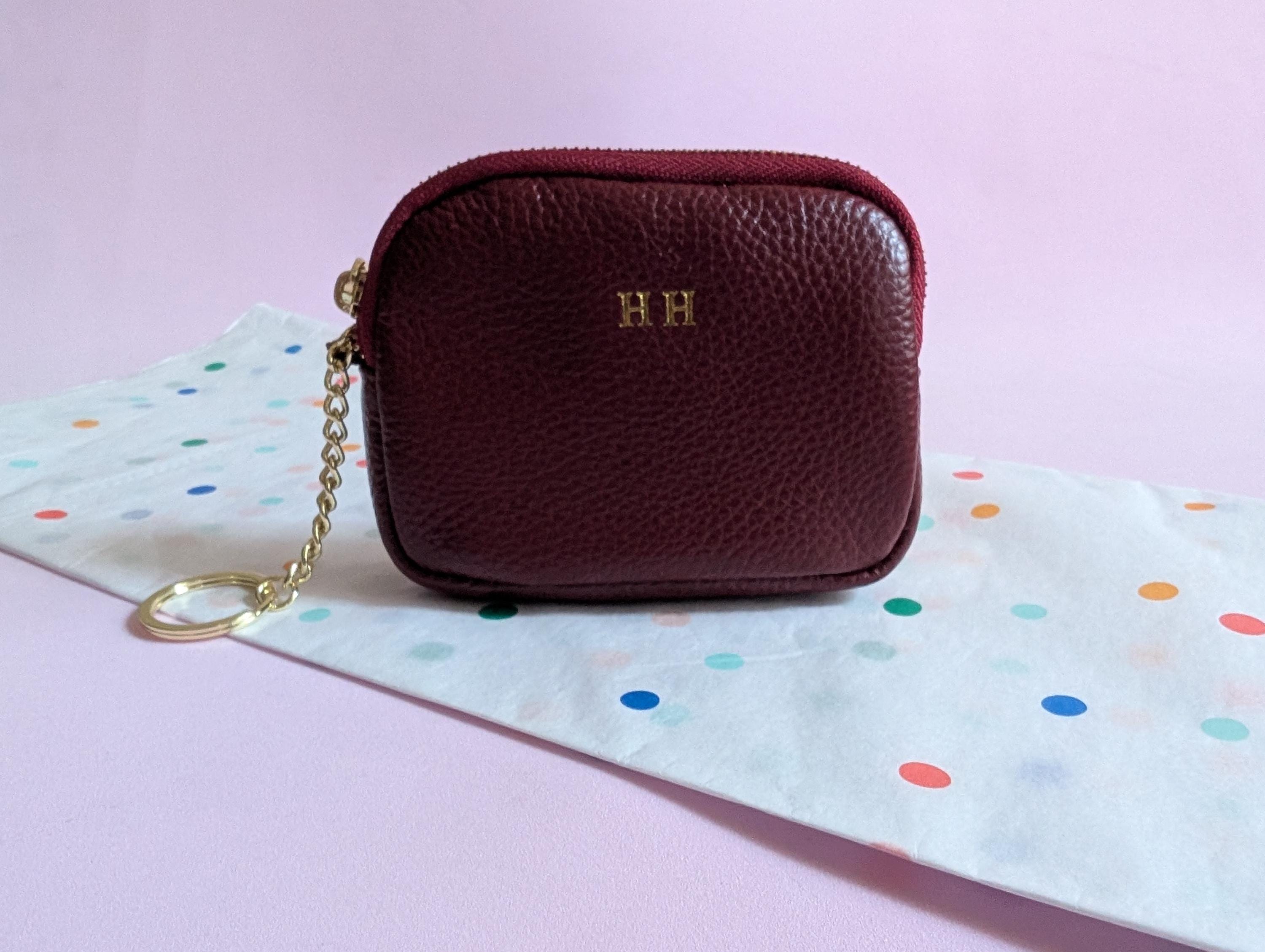 Maroon leather pouch with gold chain on a polka dot fabric background