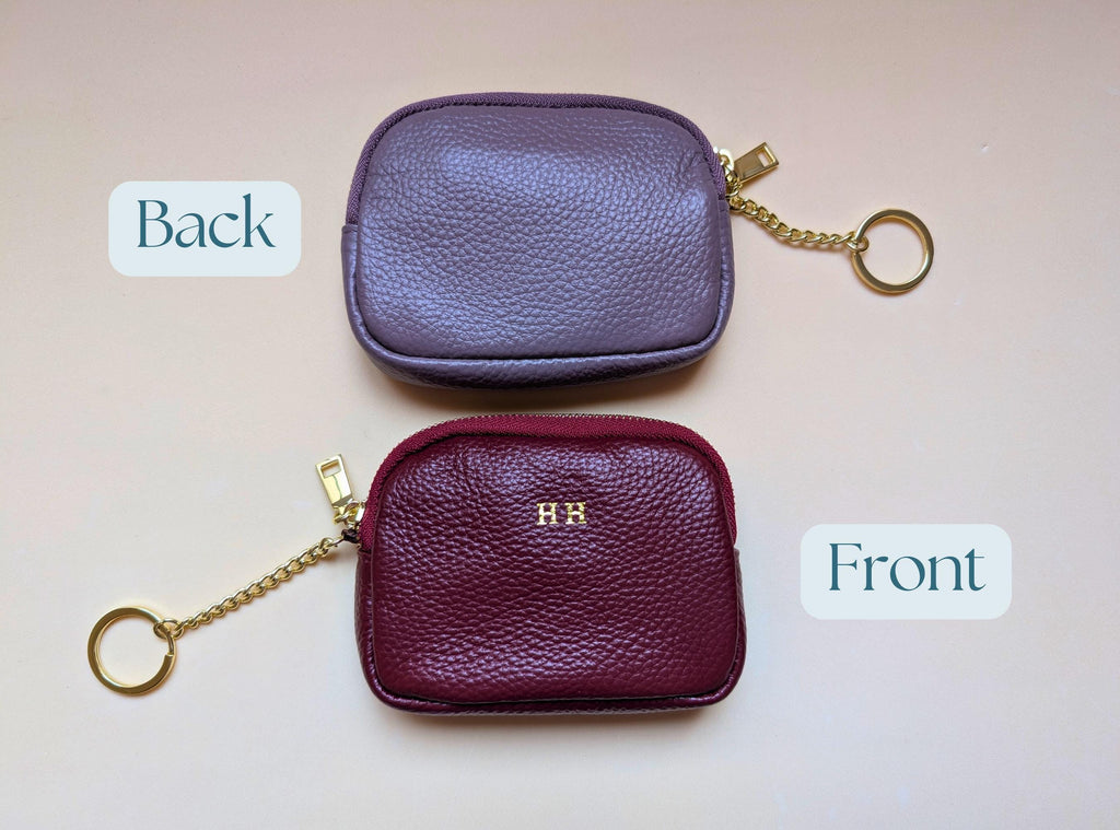Two purple leather coin purses, one labeled 'Back' and one labeled 'Front', on a light pink background.