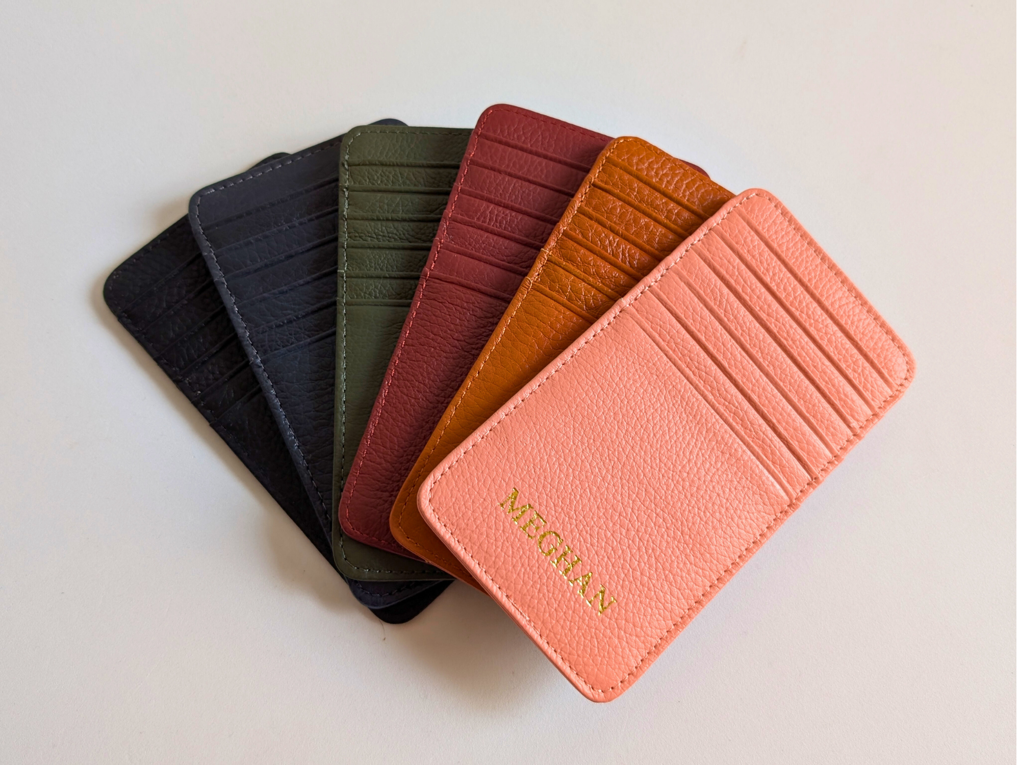 Set of five leather card holders in different colors on a light background