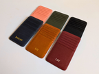 Eight leather card holders in different colors with initials engraved on a light gray background