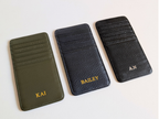 Three leather card holders with personalized names on a white background