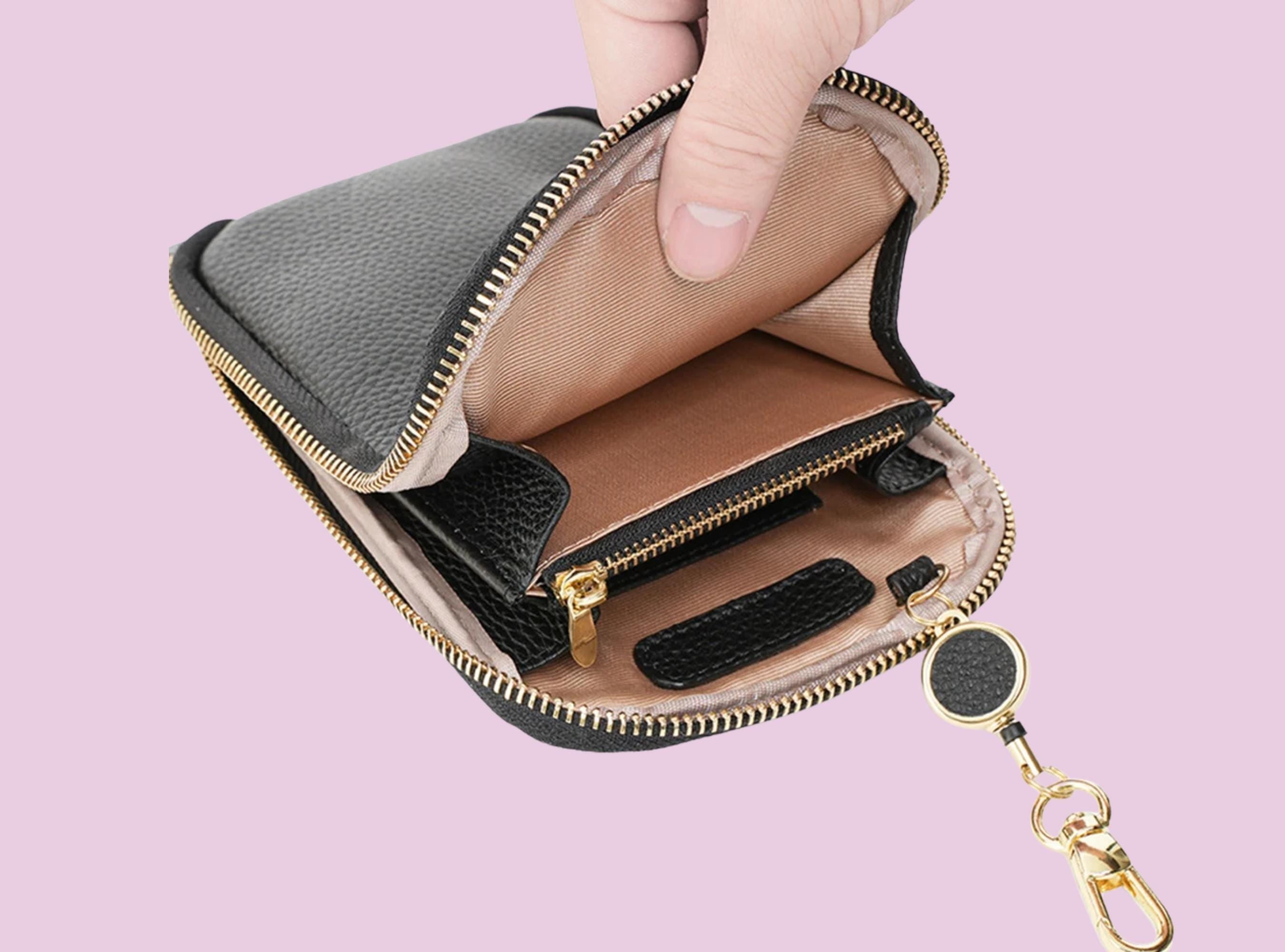 Hand holding an open black wallet with a pink background