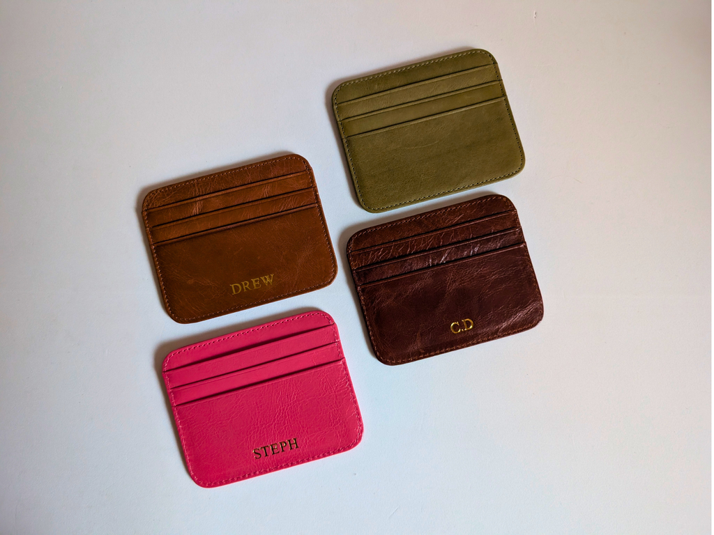 Four leather card holders in different colors on a light background