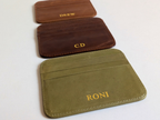 Three leather card holders with personalized names on a white background.