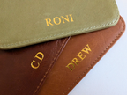 Two leather-bound books with custom names and initials embossed on a white background
