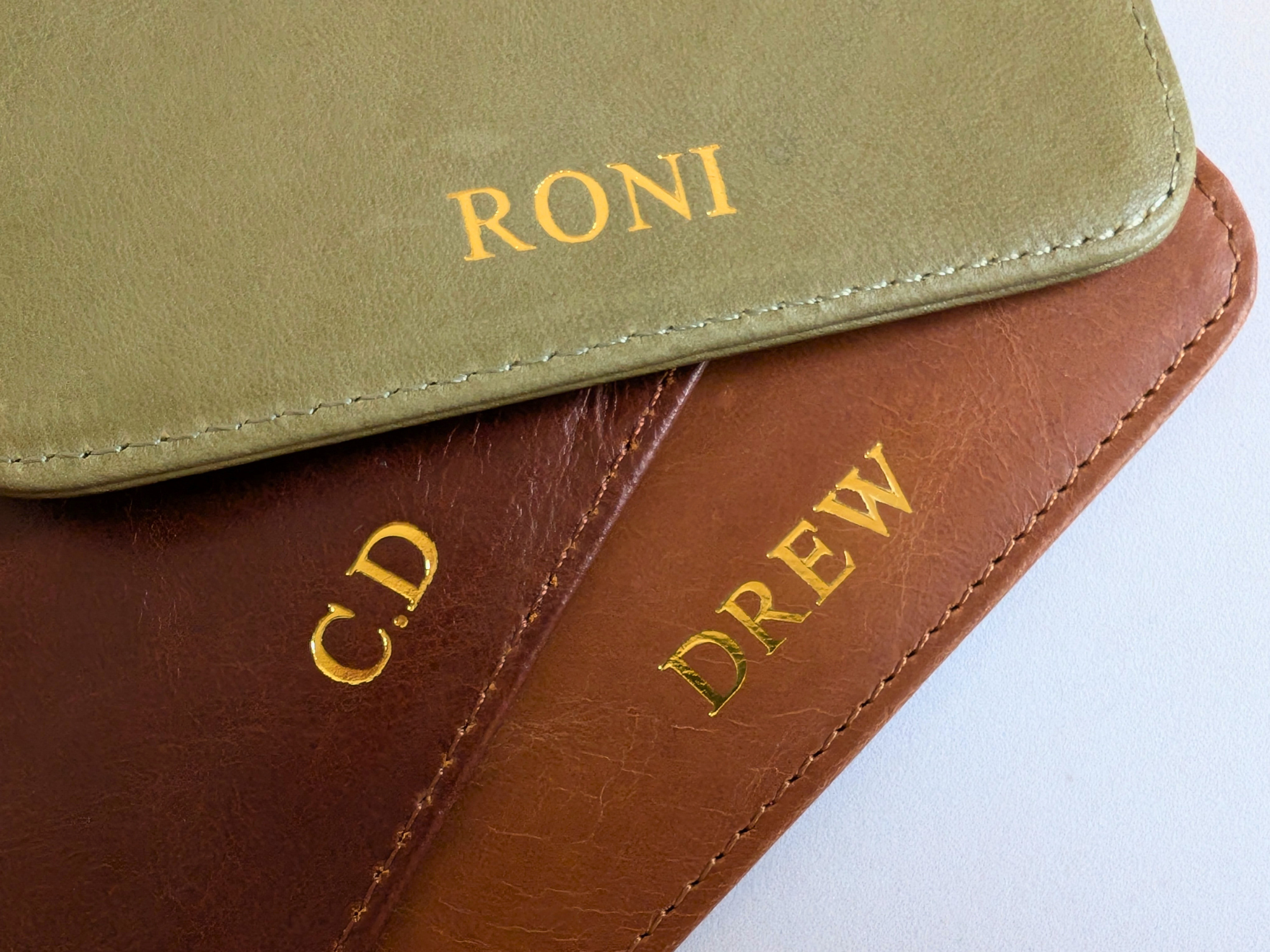 Two leather-bound books with custom names and initials embossed on a white background