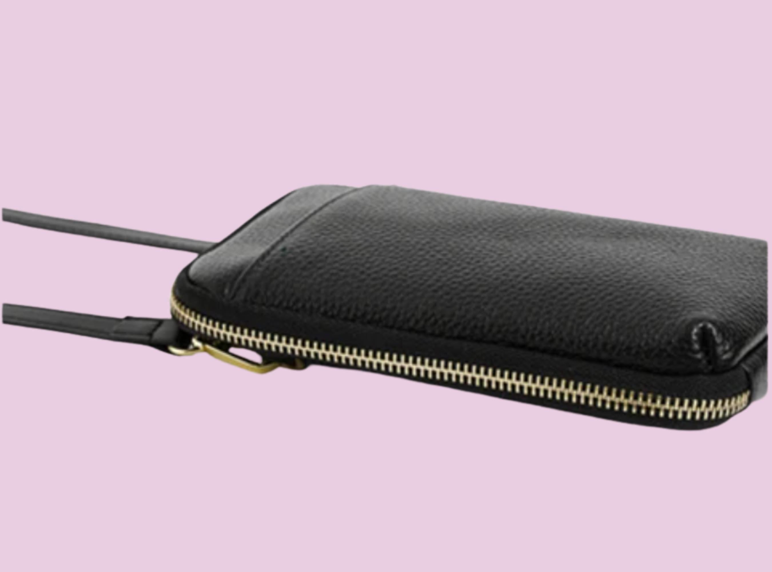 Black leather pouch with a gold zipper on a pink background