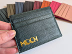Black leather cardholder with custom emobssed logo held by a hand, with color swatches in the background.