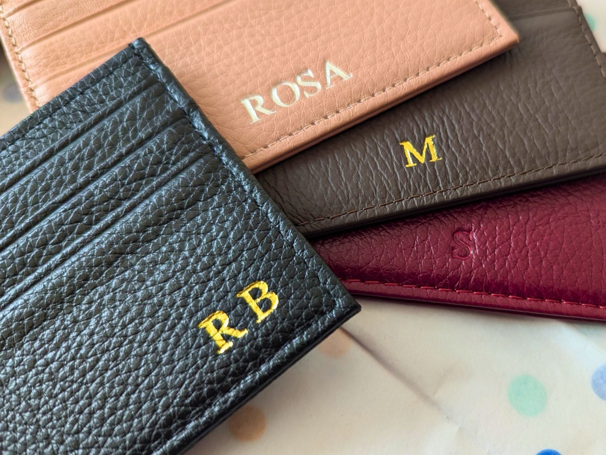 Collection of leather wallets in different colors with personalized initials embossed.