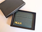 Green leather cardholder with custom branding in a black box on a light background