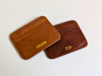 Two brown leather card holders with custom engraved on a white background.