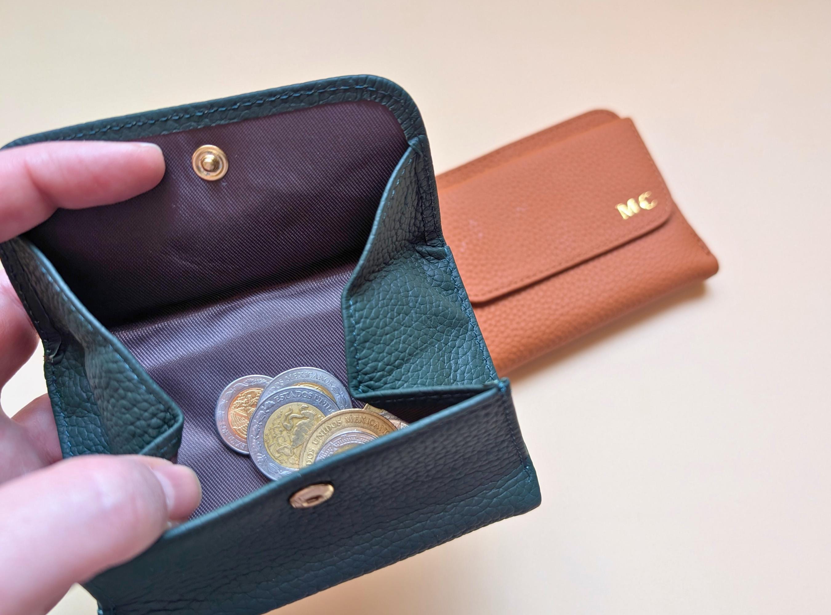 Green leather wallet with coins and a brown wallet in the background