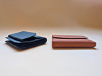 Two leather wallets, one blue and one brown, on a light beige background.