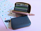 Blue wallet with a pink interior showing cards on a polka dot background