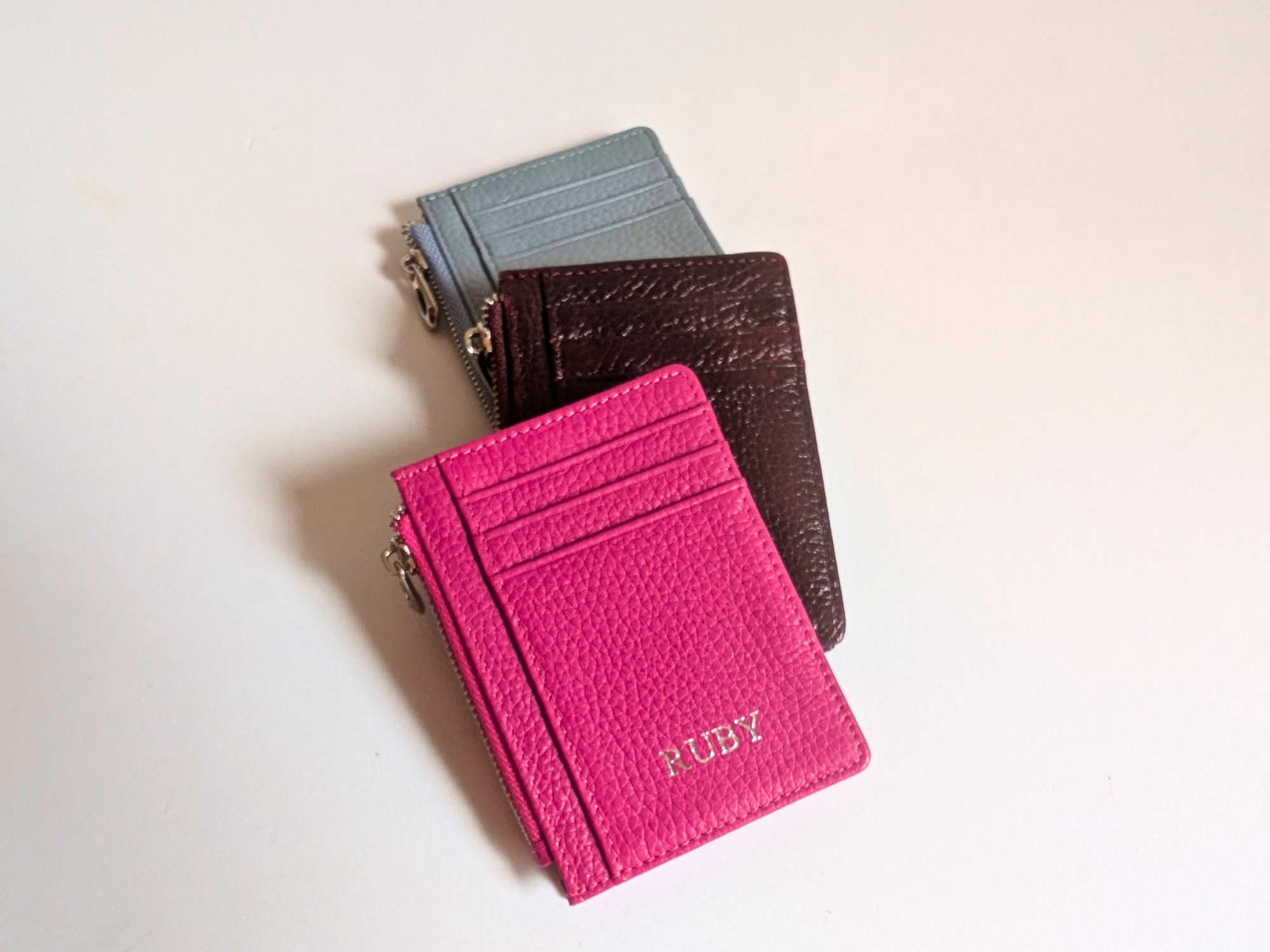 Hot Pink, Wine and Sky Blue card holders on a light background