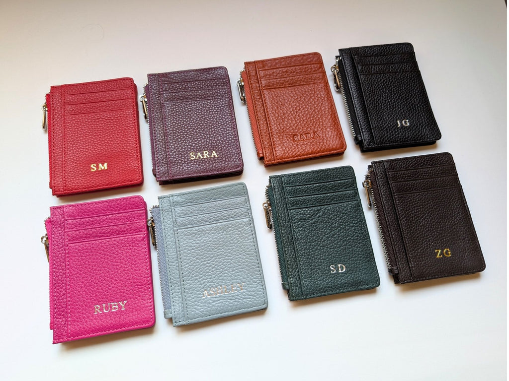 Collection of colorful leather wallets with initials on a light background with custom emboss initials. 